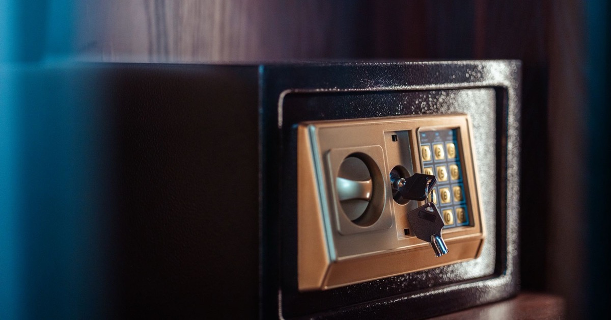 Close-up of a black electronic safe with a keypad and backup keys inserted in the lock.